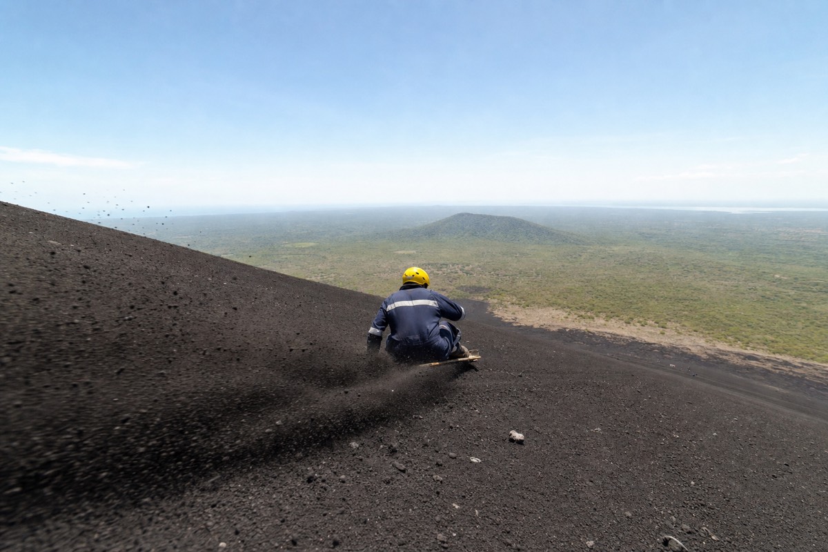 A rider sliding down the black ash slope of Cerro Negro volcano on a board near Leon, Nicaragua